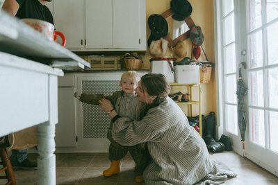 mom helping son put on jacket during to take family photos captured by NYC family photographer Elsie Goodman