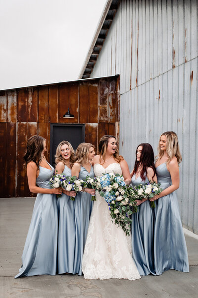 Bridesmaids wearing a soft blue dress smiling and laughing together