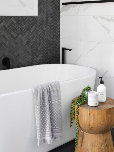 Modern bathroom with a freestanding bathtub, herringbone tile, and minimalist decor.