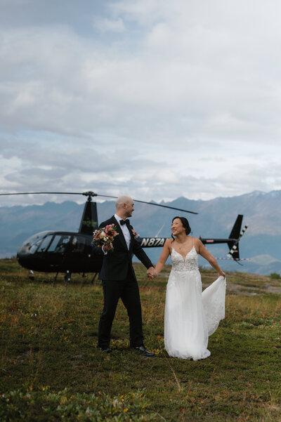 bride and groom walk in front of helicopter during elopement