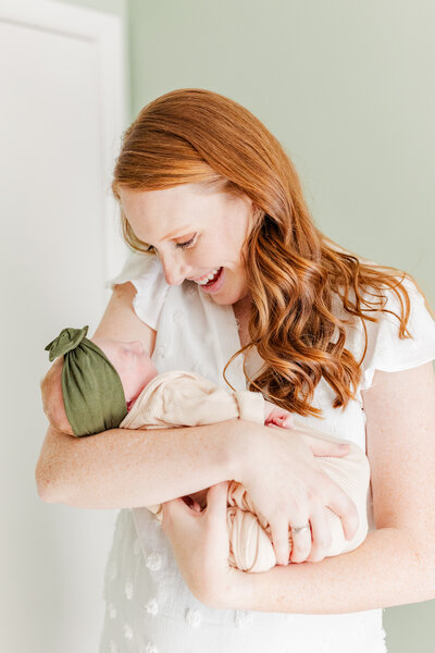 woman smiling at her newborn baby