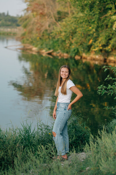 A man is on one knee proposing to his girlfriend who is jumping up and down at the Red Bridge in Des Moines Iowa by Omaha Wedding Photographer Anna Brace
