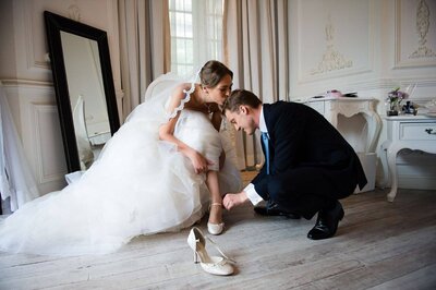 bride kiss groom when he helping her put on wedding shoes