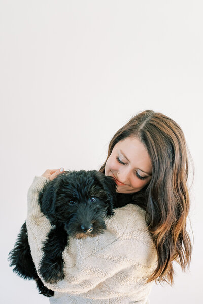 woman holding black puppy