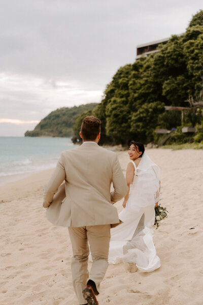 Groom chases his bride through the beach in Bali Indonesia 