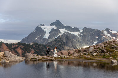 Bride and groom are walking with mountains behind them