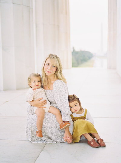 A mother sits with her two daughter in the Lincoln Memorial photographed by Northern VA Family Photographer Marie Elizabeth Photography