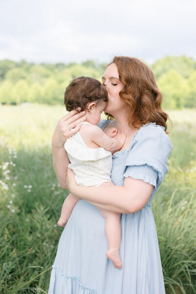 New mom wearing a cream Nothing Fits But dress holding her newborn baby boy  in a timeless northern kentucky newborn photography studio