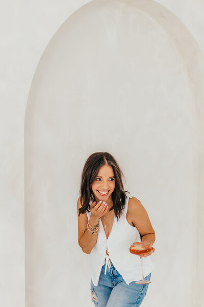 Laughing so hard at my own chaos after spilling champagne on myself- glass in hand, other hand on mouth, because sometimes you've got to embrace the joyful chaos.