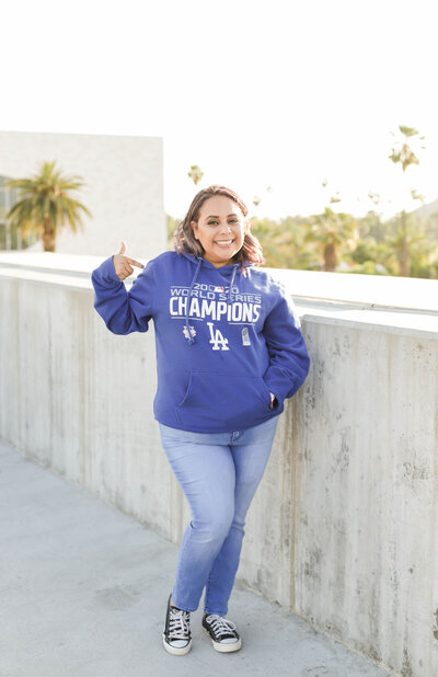 Woman standing on roof top while pointing to her dodger wear