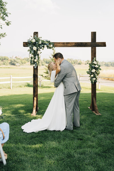 bride and groom kissing outside the Logan LDS Temple bride holding white and blue wedding bouquet