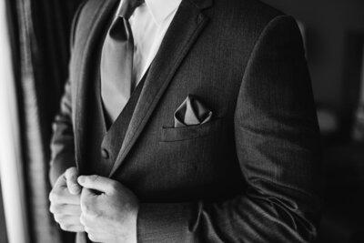 elegant black and white close-up of groom's jacket and pocket square before wedding