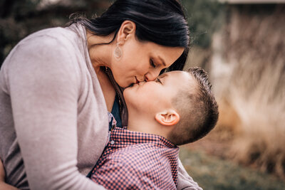 A close up image of a mom kissing her young son during a family session by Minnesota photographer Kate Simpson.