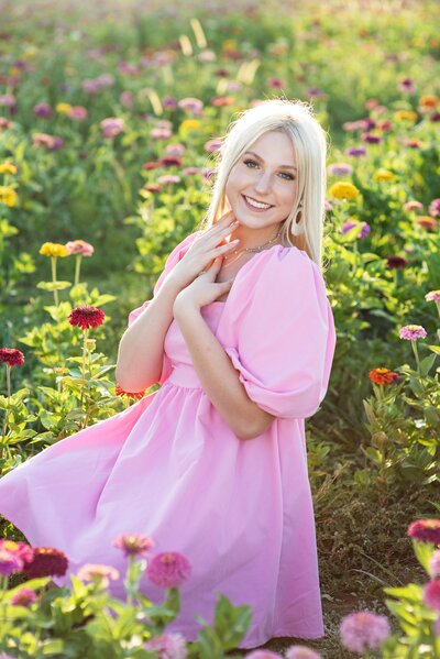 picture of high school senior girl in a field of zinnias wearing a pink dress