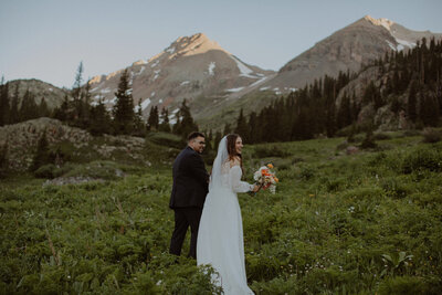 Couple holds hands and walks through Telluride mountains during their elopement