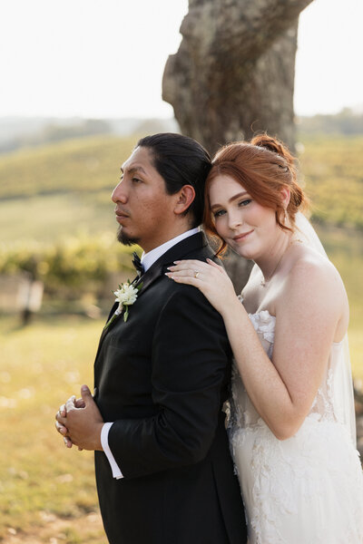 Couple shares a romantic kiss under a delicate veil, captured in a soft, intimate moment.