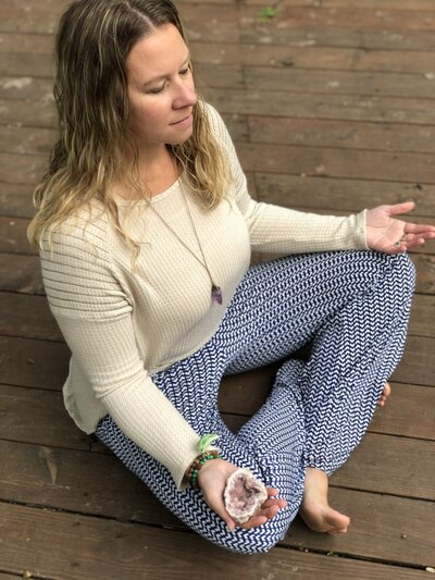Andrea holding a amethyst crystal  meditating outside