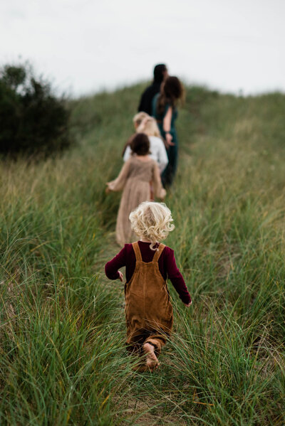 Family Photographer, family of six walking up a grassy hill