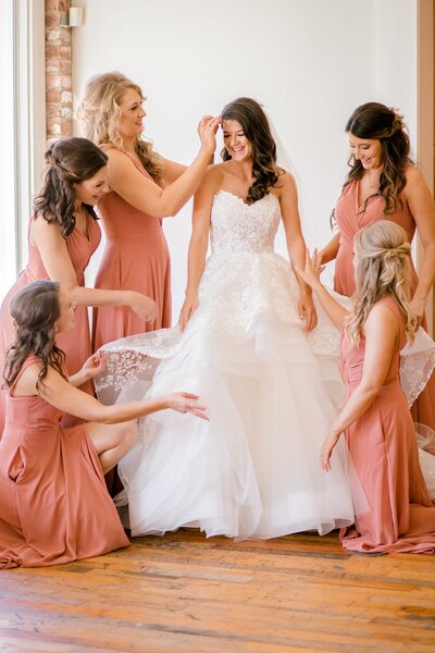 Bridesmaids helping bride get dresses