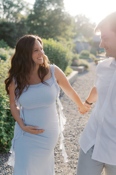Pregnant mom and husband hold hands at the University of Tennessee Botanical Gardens in Knoxville, Tennessee