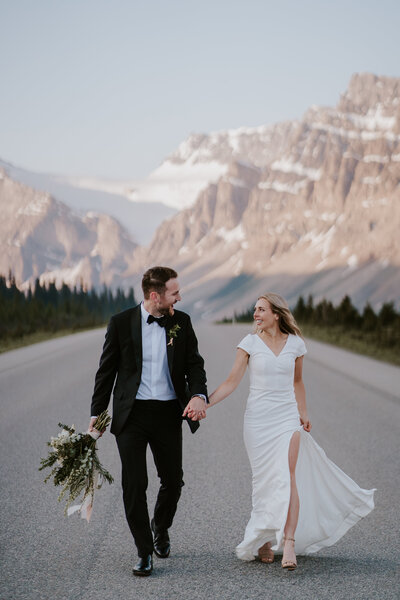 Eloping couple holding hands on the Icefields Parkway in Banff Nat