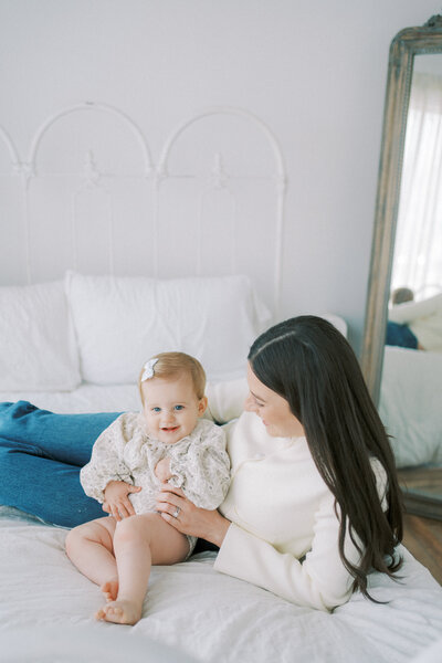 mom playing with daughter on bed