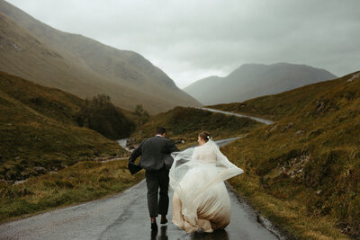 bride and groom running in the scotland hills