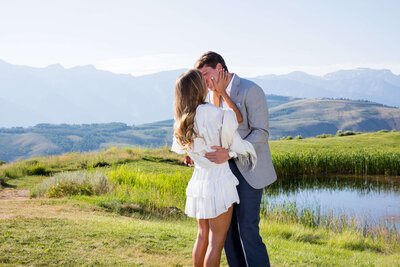 A couple poses together in a meadow during their Amangani Grand Teton engagement session, with the Grand Teton mountains towering behind them.