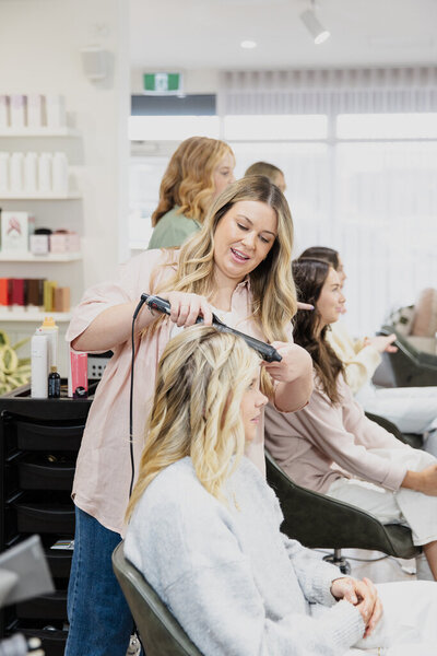 A woman curling blonde hair in a hairdressers