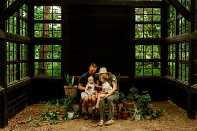 Family of four in a black greenhouse with green plants