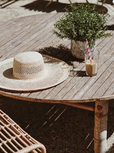 Sun hat on outdoor table with green plant