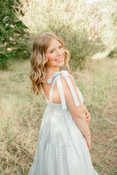 Senior girl smiling at camera in a green grassy field