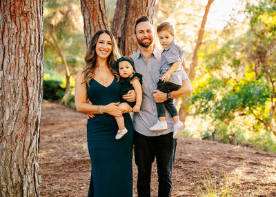Family smiling at family session in wooded forest in Orange County, CA by Ashley Nicole Photography.