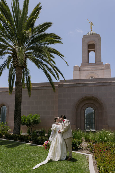 Yered kissing his bride in front of the Newport LDS Temple.