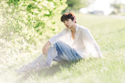 male sitting on grass with large bushes in albany ny