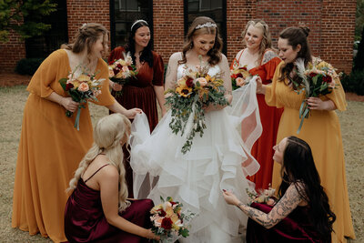 A bride is surrounded by her bridesmaids as they fluff her dress at The Cotton Press in Little Mountain, South Carolina.