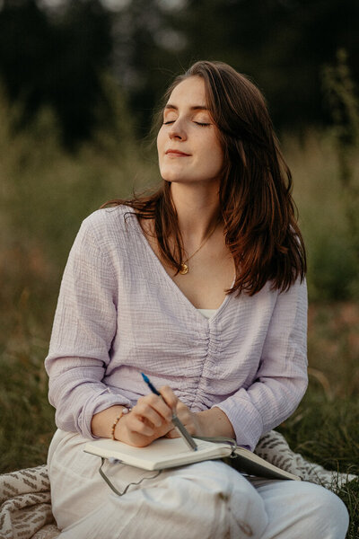 Tessa Adrian in einer meditativen Yoga-Haltung im Grünen, voller Achtsamkeit.