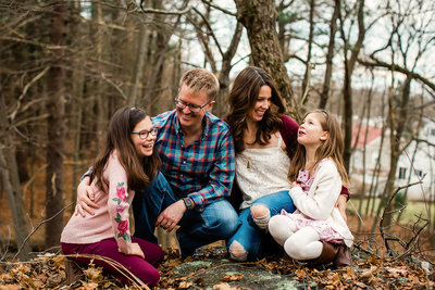 Mom and dad and two daughters on grass in woods