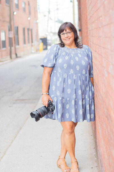 Photographer Claire Spampinato smiles in jean jacket and striped top by a river