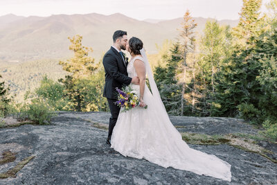 Bride and Groom kissing after their first look at the summit of a mountain during sunrise in Keene Valley
