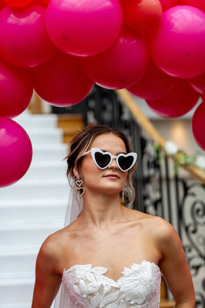 Bride stands under pink balloons 