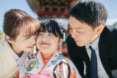 お寺の境内で顔を寄せ合っている自然な笑顔の親子、家族のつながりを感じる七五三の写真