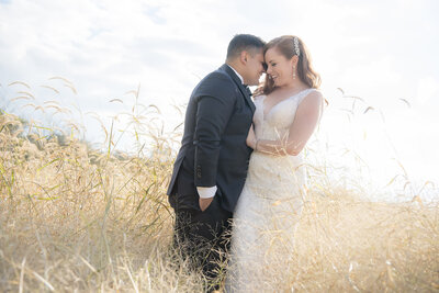 A person leaning into their partner as they stand in a field on their wedding day 