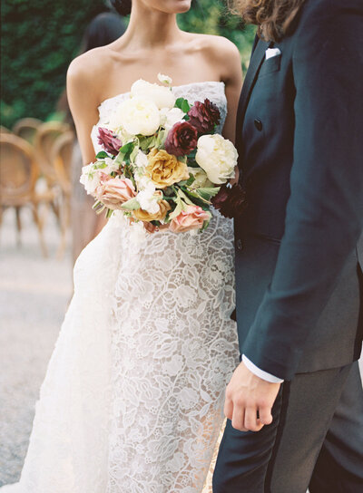 Bride in strapless lace gown with bouquet embracing groom at Greencrest Manor