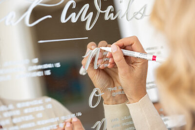 Close up of Connecticut calligrapher writing on a seating chart mirror