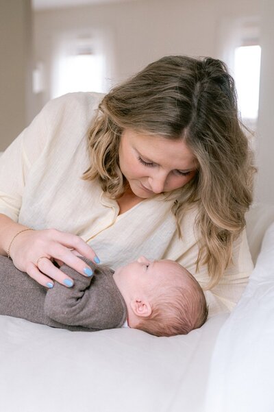 Mama ligt met newborn baby in bed voor een Leidse newborn shoot