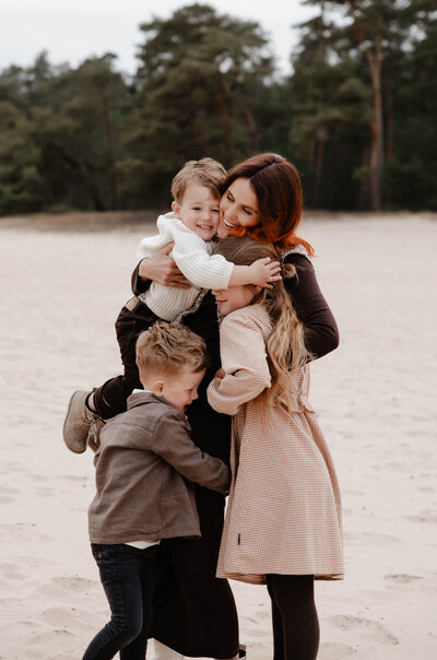 Moeder met drie kinderen aan het knuffelen