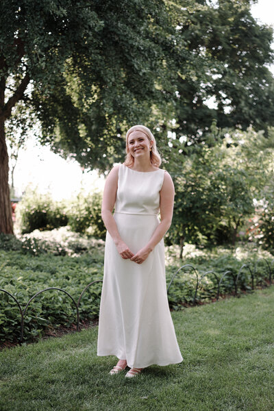 The bride laughing joyfully in a lush green space, captured in a candid moment that reflects her happiness on her wedding day