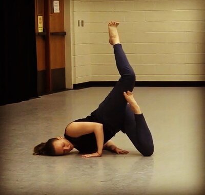 Woman in a modern dance position with her head on the floor and her legs lifted into the air