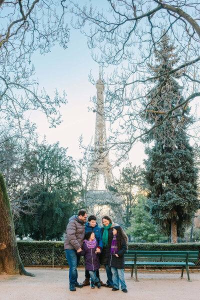 Mother, Father and three children posing outside the Eiffel Tower on Family photoshoot session in Paris
